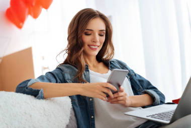 在家使用智能手機的微笑的少婦