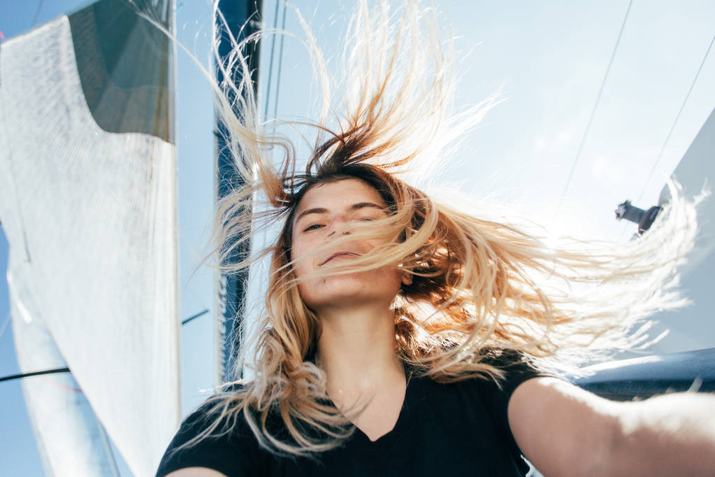 年轻美丽的金发女人使自拍在游艇上, 风吹头发  年轻美丽的金发女人使自拍在游艇上, 风吹头发