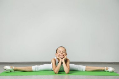 年轻姑娘做绿色瑜伽垫上练习