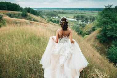 一個(gè)快樂的新娘穿著婚紗, 在美麗的自然背景下奔跑