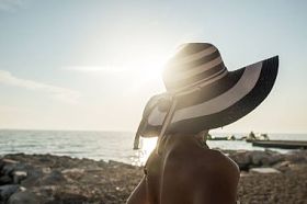 在海滩上看日落的女人在泳衣后视图