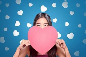 蓝色背景手捧红心的年轻亚裔妇女