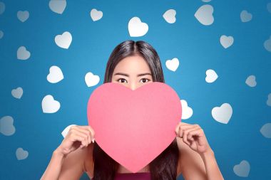 蓝色背景手捧红心的年轻亚裔妇女 蓝色背景手捧红心的年轻亚裔妇女