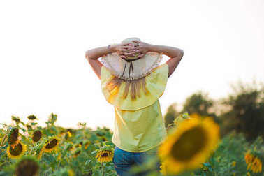 年輕時尚婦女與太陽花和在時髦的帽子和藍(lán)色牛仔褲短褲