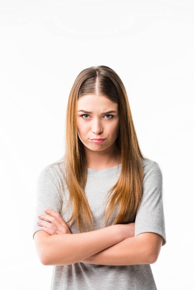 雙臂交叉的情感女性肖像看著在白色的相機隔離