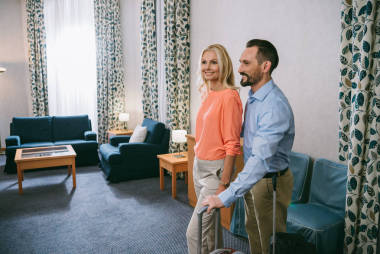 微笑成熟夫婦與手提箱站在一起在酒店房間