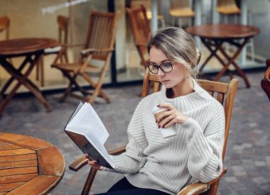 美丽的年轻女子读一本书, 一杯咖啡