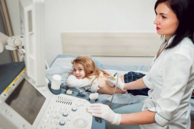 女医生和小金发女孩的病人。超声波设备。诊断.超声