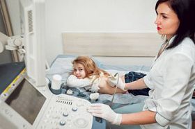 女医生和小金发女孩的病人。超声波设备。诊断.超声