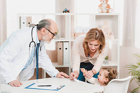 母亲和哭泣的小女儿在诊所接受医生