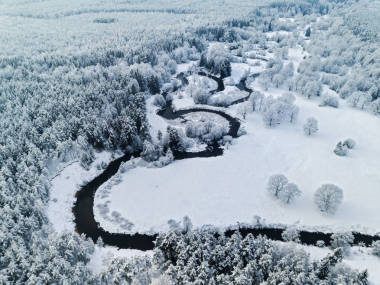 神奇的野生河流在冰凍的森林北方的冬天下雪了空中全景