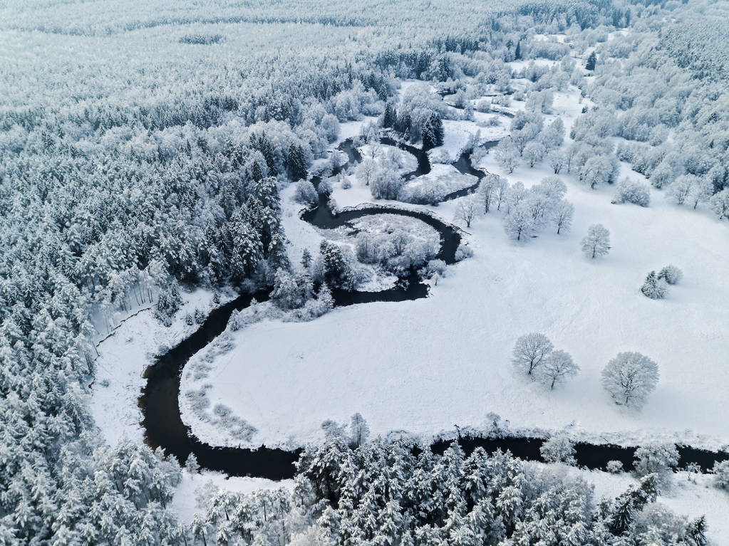 神奇的野生河流在冰冻的森林北方的冬天下雪了空中全景