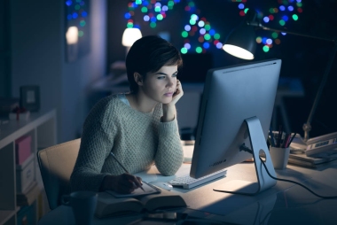 深夜工作和學(xué)習(xí)的年輕女子, 她正在與她的電腦連接, 并在記事本上寫下筆記