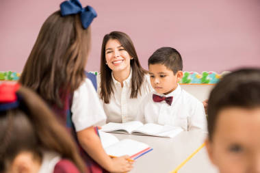 快樂(lè)的年輕黑發(fā)教學(xué)齡前和享受他的工作與她的小組學(xué)生