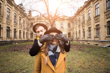 戴手套的男人闭上眼睛的女人面前的建筑