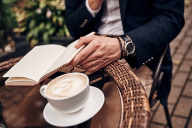 论商务男子在餐桌上拿着卡布奇诺杯的日记