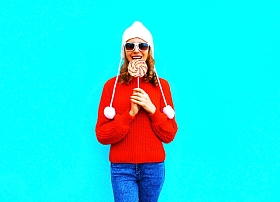 肖像俏丽的微笑的妇女咬住棒糖红色针织 sw