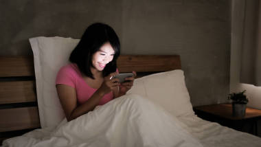 在晚上愉快地玩手机游戏的妇女