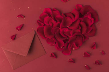 紅玫瑰花瓣和信封的心的頂部視圖紅色, st 情人節(jié)概念