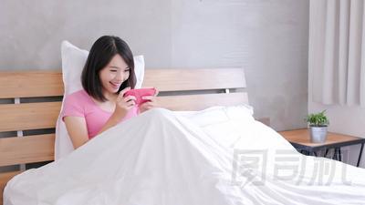 在床上愉快地玩手機游戲的婦女