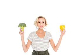 美丽的年轻女子抱着新鲜的花椰菜与胡椒和微笑在镜头上的白色隔离