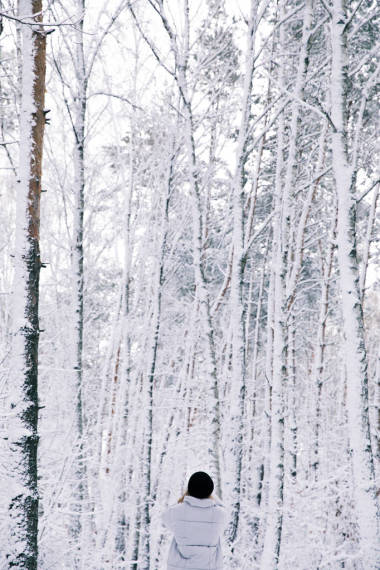 在白雪皚皚的森林里行走的女孩的后視圖
