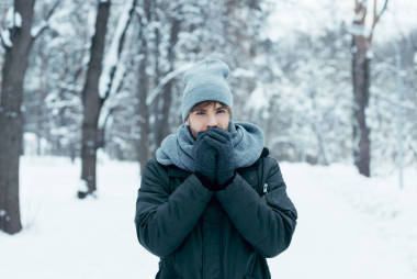 年輕男子的肖像溫暖的手在雪地公園散步