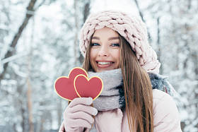 美丽的年轻女子的画像, 手里拿着心在雪地公园里看镜头