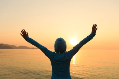 站在日出風(fēng)海岸的歡呼女性剪影