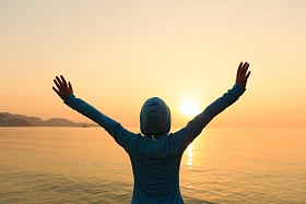 站在日出风海岸的欢呼女性剪影