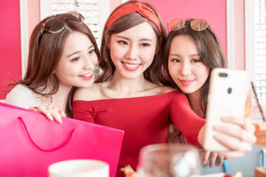 购物袋的妇女在餐馆愉快地采取自拍