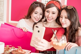 购物袋的妇女在餐馆愉快地采取自拍