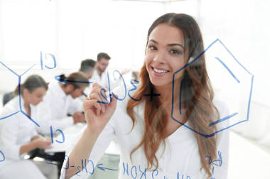 微笑的女助手在黑板上做一項(xiàng)