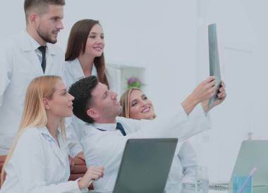 微笑的醫(yī)生是 analyzind x 光片。醫(yī)療辦公室室內(nèi)