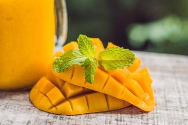 芒果冰沙在一個(gè)玻璃梅森罐子和芒果在一個(gè)綠色的 backgro