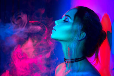 在五顏六色的明亮的燈與煙的婦女用時髦做