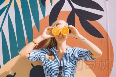 年輕快樂的女人擺著橙色反對彩色繪畫