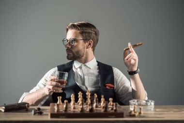 年輕人喝著一杯威士忌抽雪茄, 一邊下棋邊看一邊