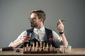 年轻人喝着一杯威士忌抽雪茄, 一边下棋边看一边