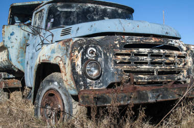 舊廢棄的骯臟的破老式卡車在彩彈場操場的中間