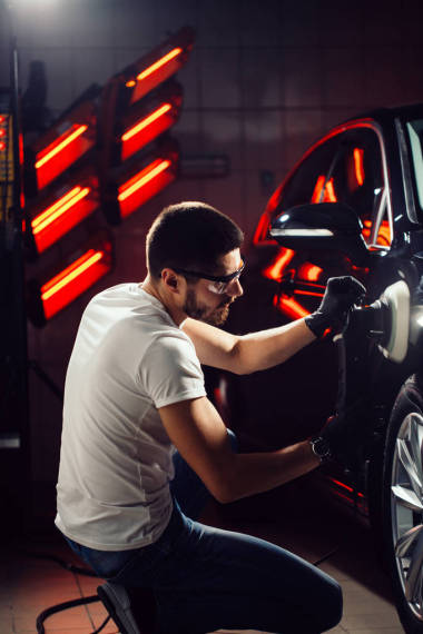 汽車修理廠-在汽車修理車間的人與軌道拋光機(jī)。選擇性焦點(diǎn)