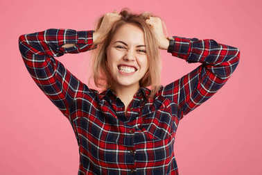 美麗的年輕女性揪的牙齒, 眼淚出來的頭發(fā), 遺憾的東西, 在失去和非常情緒化, 在粉紅色背景隔離。人、情感和感覺概念