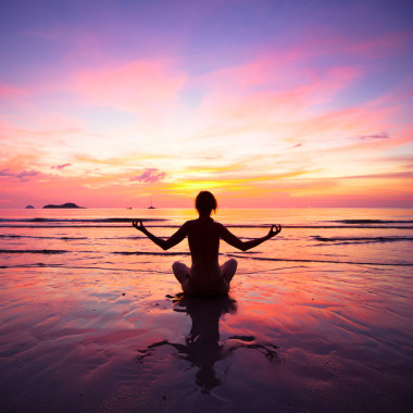 練瑜伽在夕陽(yáng)西下的時(shí)候坐在沙灘上一個(gè)女人
