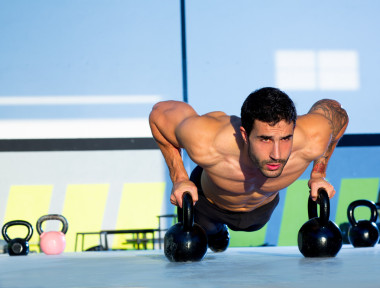 健身房男子俯臥撐強(qiáng)度伏地挺身與 kettlebell