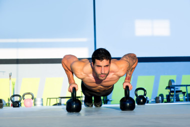 健身房男子俯臥撐強度伏地挺身與 kettlebell