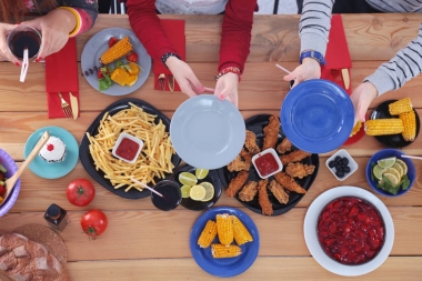 顶视图的一群人在一起时坐在木桌吃饭。在桌子上的食物。人们吃快餐