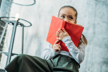 可爱的小孩子在眼镜覆盖面与书