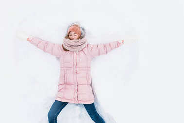 快樂的女人躺在雪地里, 胳膊和腿上下移動, 創(chuàng)造了一個(gè)雪天使的形狀。微笑的婦女躺在雪地上的寒假, 為廣告