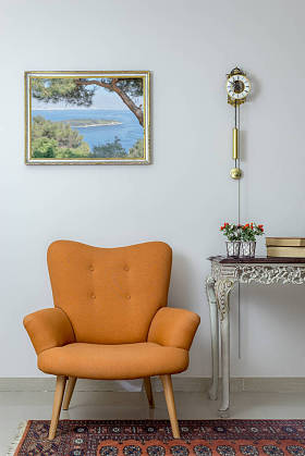 复古橙色扶手椅的内部组成, 老式木米色表, 和钟摆时钟在白色的墙壁, 瓷砖米色地板和橙色华丽的地毯