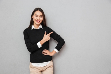 微笑亞洲婦女在商業(yè)衣裳與胳膊在臀部